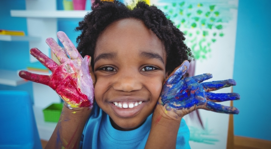 Happy child smiling with paint on hands