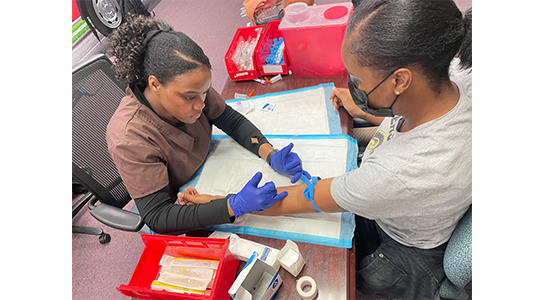 Phlebotomy students practicing venipuncture procedure in lab